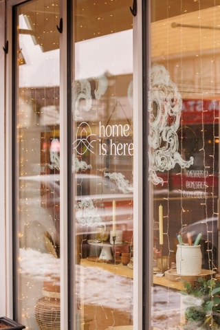 Home is Here store front window with logo and string lights